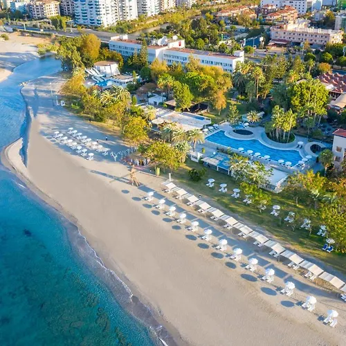 Labranda Alantur Hotel Alanya Beach photo This is an aerial view of a beautiful beach resort. The resort is situated along a sandy beach with clear turquoise water. The beach is lined with rows of white sun loungers and umbrellas, suggesting a relaxing vacation spot. 

Behind the beach, ther